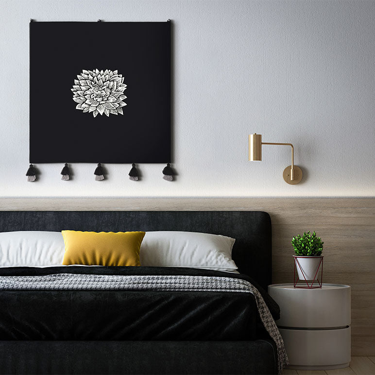 Modern bedroom with black headboard, yellow pillow and black Dahlia embroidered wall hanging