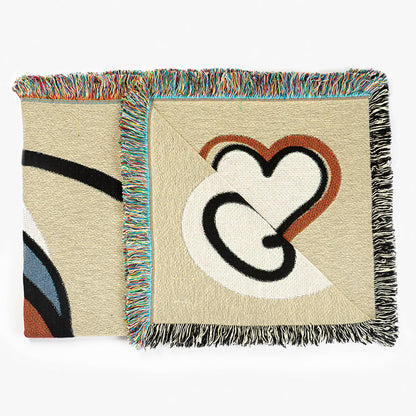Folded designer throw blanket with a heart design and colorful fringe on a white background