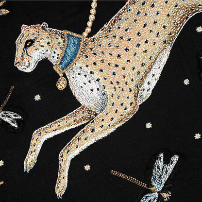 Embroidered cheetah design on a black throw blanket with decorative elements.