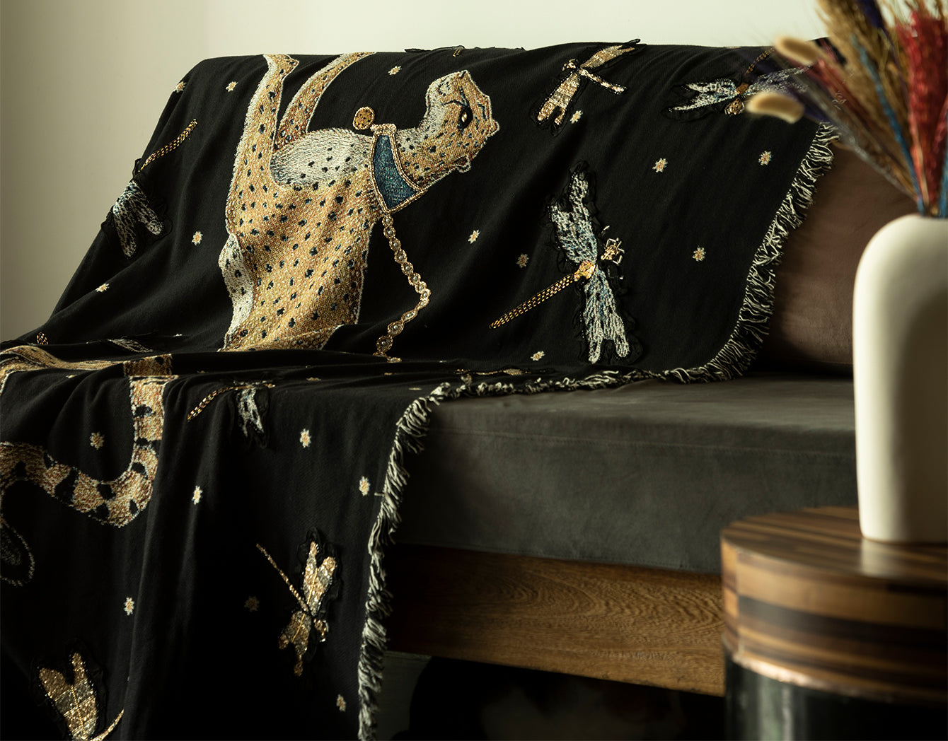 Decorative black blanket with embroidered cheetah design draped over a sofa.
