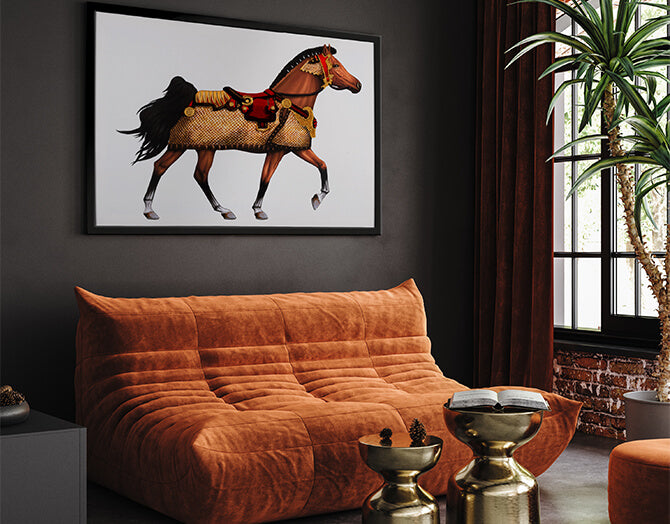 Framed artwork of a horse on a dark wall above an orange sofa in a room with a plant and window.