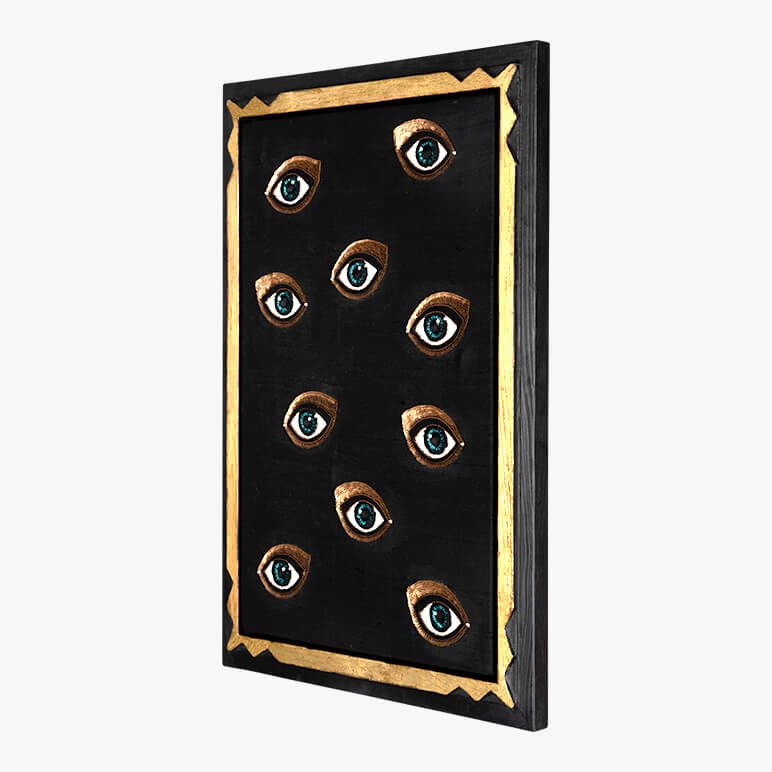 Decorative wall art with eyes on a black background with gold frame