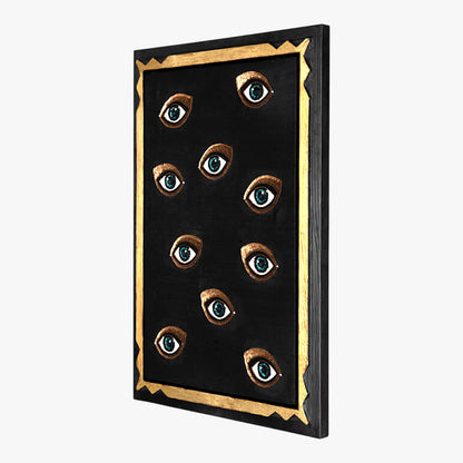 Decorative wall art with eyes on a black background with gold frame