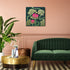 Living room with green sofa, gold coffee table, and floral wall art on a pink wall.