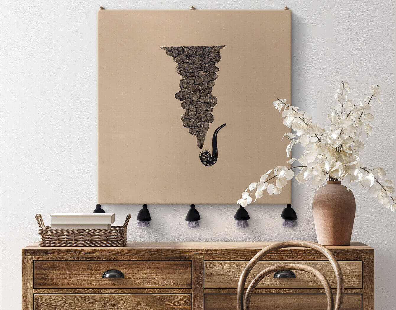 Decorative wall hanging with an embroidered smoking pipe on a dark beige background, displayed above a wooden console table.