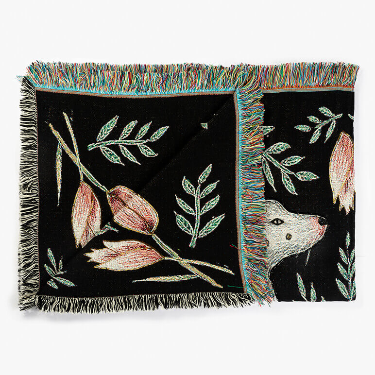 Decorative throw blanket with floral and animal patterns on a white background