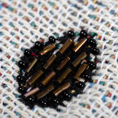 Close-up of a beaded heart-shaped object on a textured fabric background