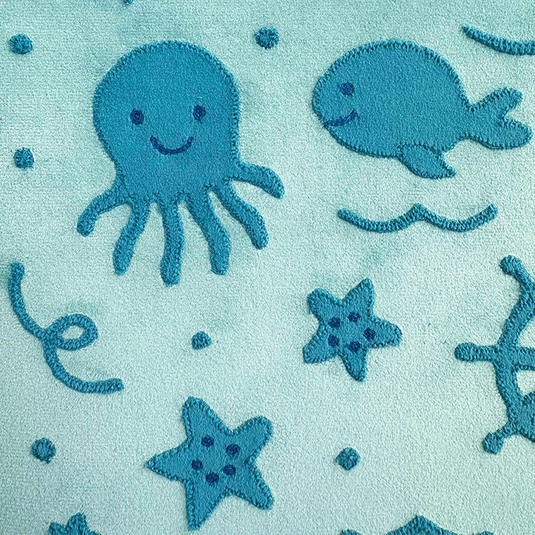 Teal fabric with embroidered blue octopus, whale, starfish, and sea anemone on a light blue background.