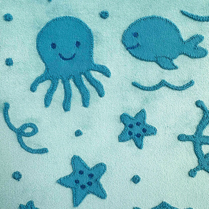 Teal fabric with embroidered blue octopus, whale, starfish, and sea anemone on a light blue background.