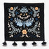 Night Garden embroidered wall hanging—moth and floral motif in blue and cream on black—hung above a grey crib with a yellow throw in a cozy nursery.
