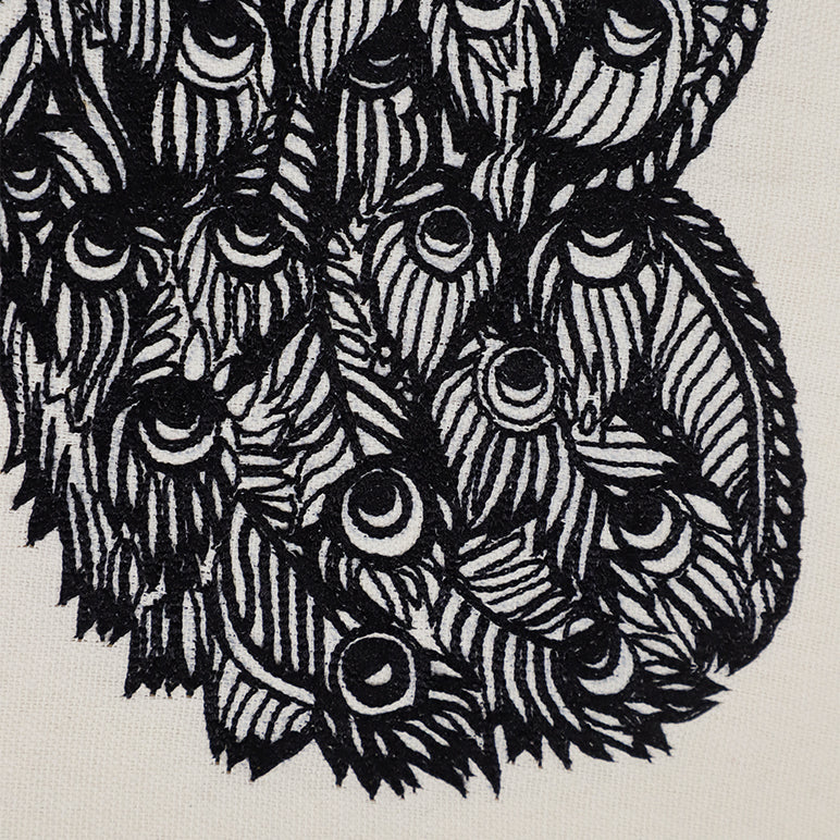 Close-up of hand-embroidered peacock feather motif in black thread on off-white embroidered wall hanging