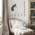 Decorative chair with pillows and a peacock wall hanging in a room setting.