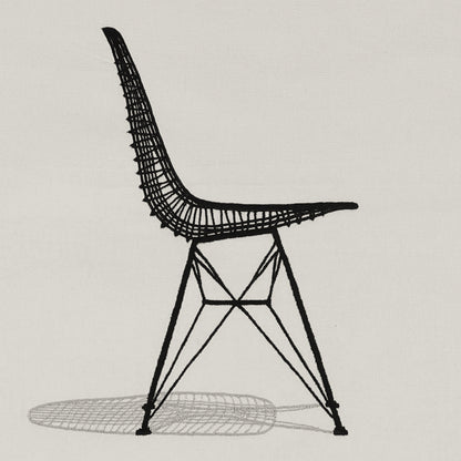 Close-up of the Sit Pretty embroidered wall hanging—black line-art chair stitched on off-white fabric with a grey shadow.