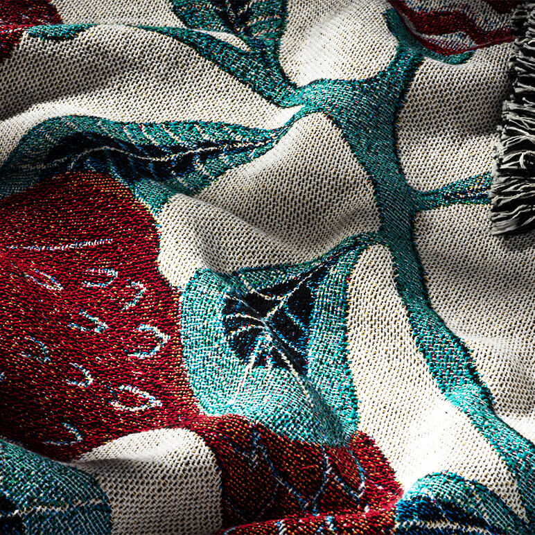Close-up of a textured cotton blanket with pattern in red, green, and beige.