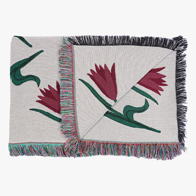 Woven tulip throw blanket with floral patterns and fringes on a white background