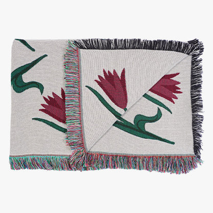 Woven tulip throw blanket with floral patterns and fringes on a white background
