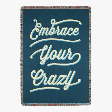 blue throw blanket with the phrase "embrace your crazy" woven on top