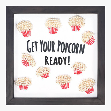 Product feature image showing a typographical artwork that says get your popcorn ready with popcorn bucket motifs embroidered around it, framed in black