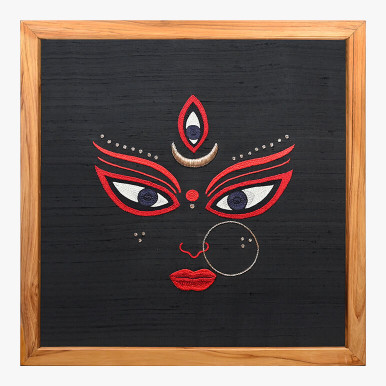 Product feature image showcasing a Goddess Durga textile art hand-embroidered in white, red and gold over a black raw silk background, framed in wood