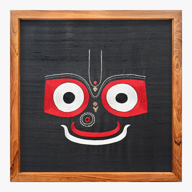 Product featuring a textile artwork showcasing Bhagwan Jagannath on a black raw silk background with the embroidery on top done in white, gold and red colors