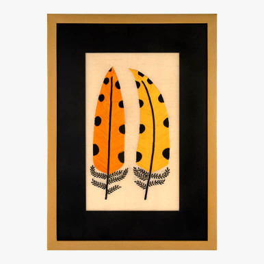 framed modern folk embroidery art featuring two yellow embroidered feathers with black polka dots