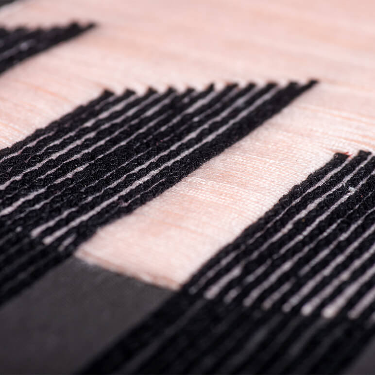 closeup view of the embroidery on a textile artwork in black and nude colors