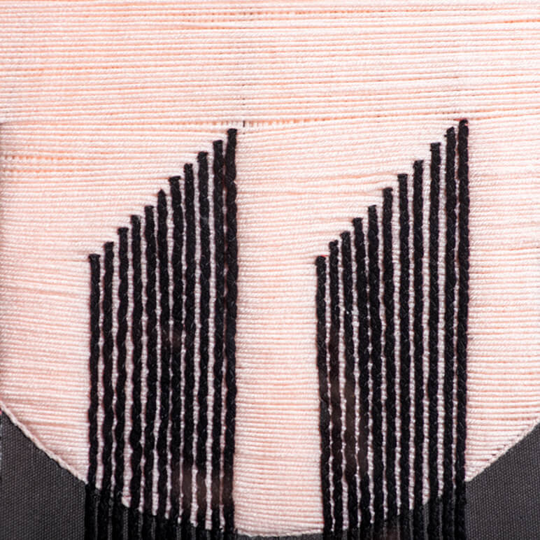closeup view of the embroidery on a woolen textile wall art piece 