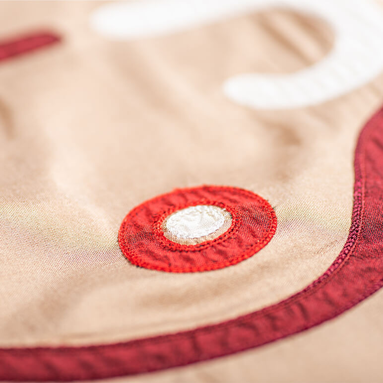 close-up view of patchwork embroidery in red and white over a golden brown background