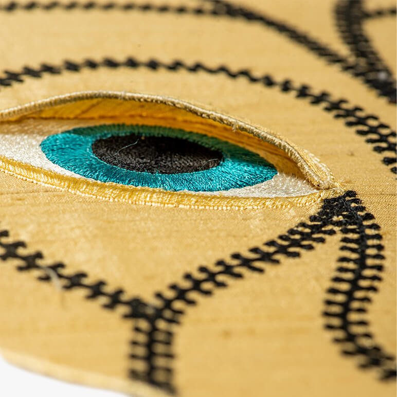 embroidered black and blue eye on a golden panther head textile art
