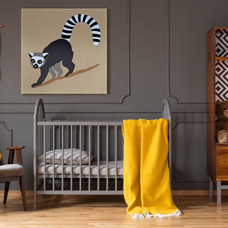 Staged image of a monochrome animal wall art piece featuring a lemur monkey in the form of a textile art, seen displayed on the wall of a modern nursery room