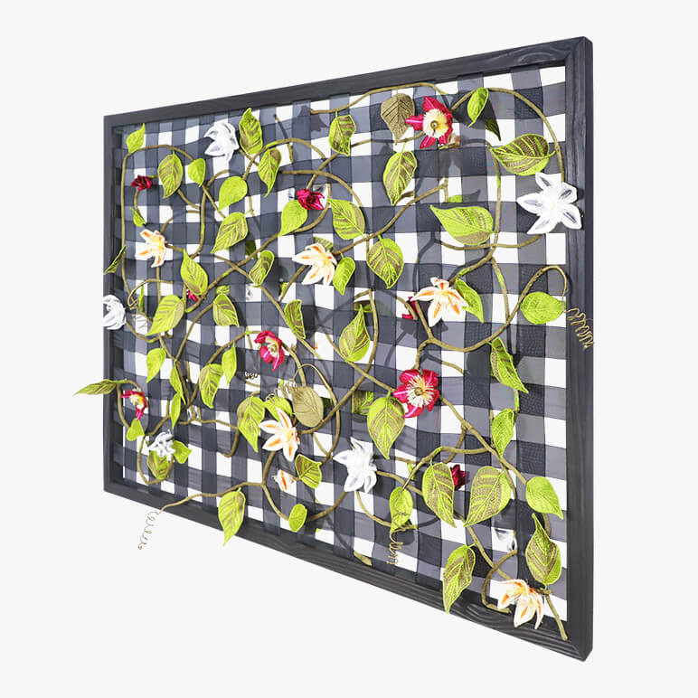 side angle view of a framed nature inspired textile art piece featuring a life-like clematis vine with all its botanical elements, all hand-embroidered in their natural colors