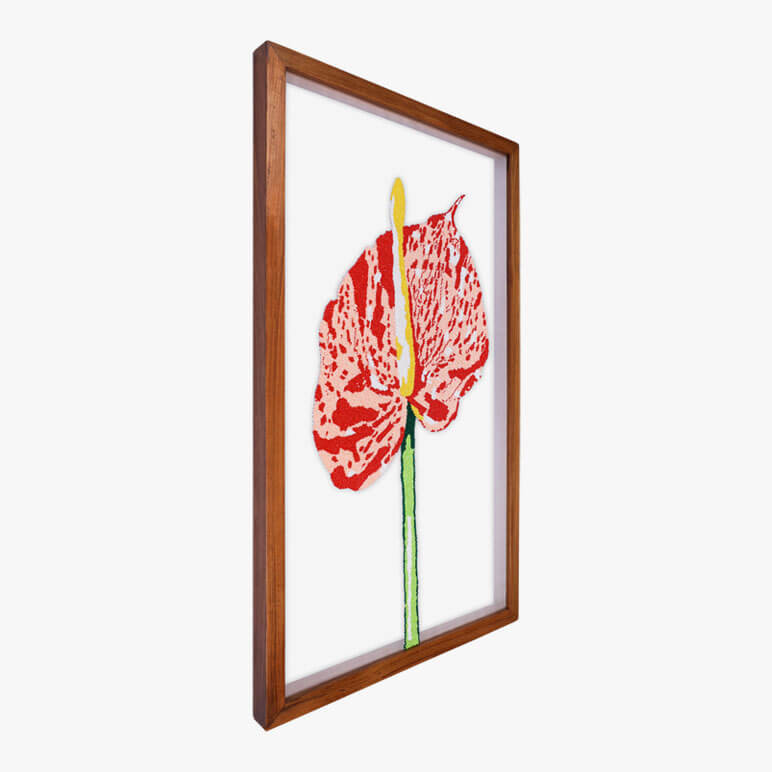 Angled view of a framed textile art with flowers, showcasing the Anthurium flower
