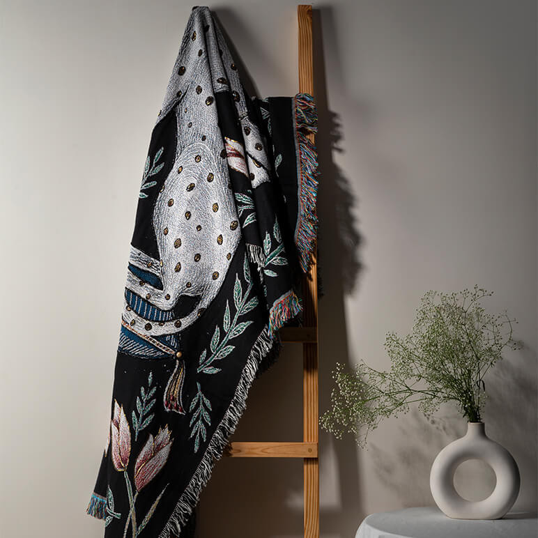 an embellished black and white throw stylistically laid on a wooden ladder
