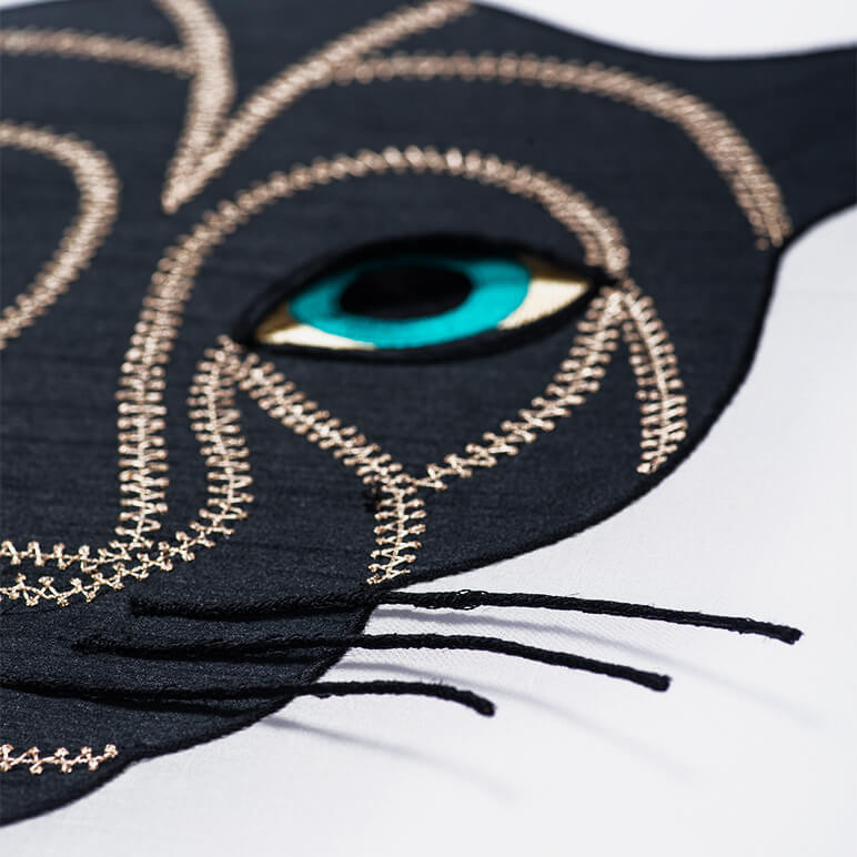 close-up view of the embroidery of a panther head patchwork textile art in black, gold and blue