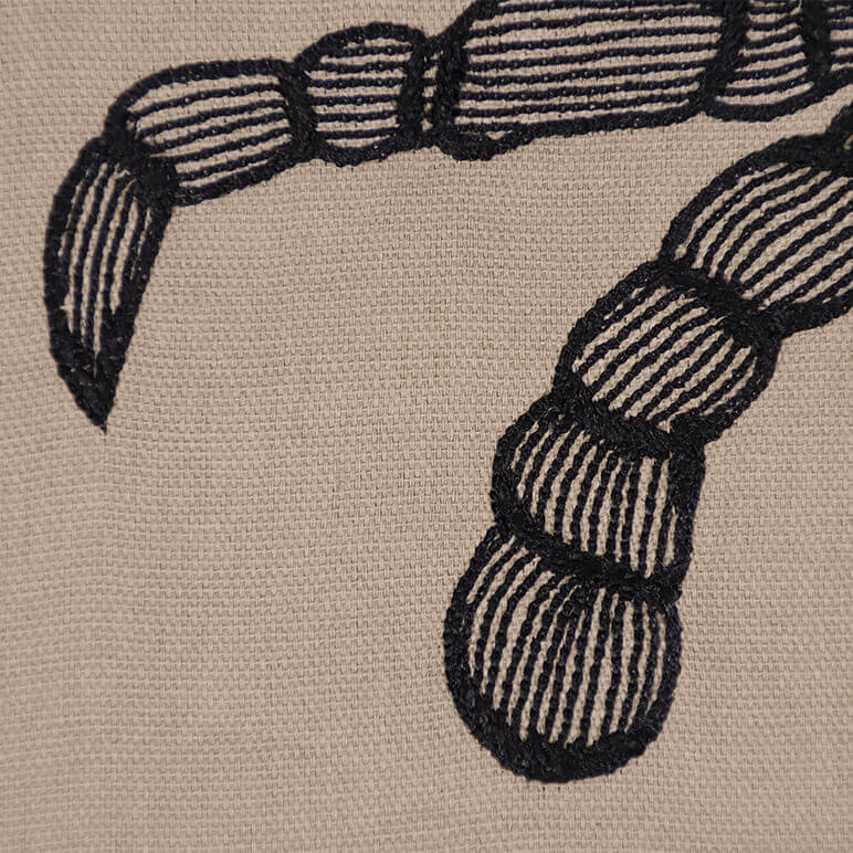 closeup view of a minimalist line embroidery of the legs of a blue crab done over a brown cotton background