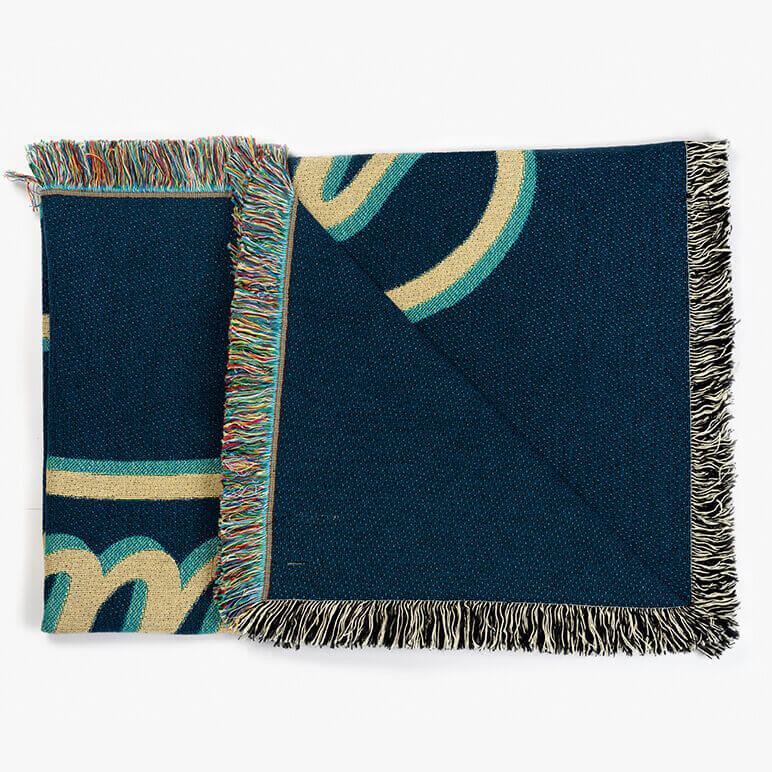 folded blue throw blanket with multicolored tassels
