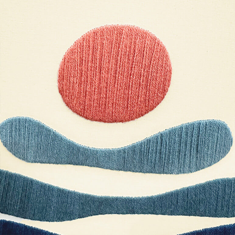 Detailed view of the woollen embroidery in salmon and blue colors, done over a beige fabric background