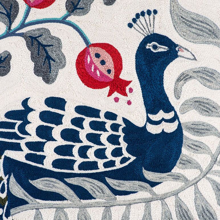 embroidery detail of a blue peacock on a white background