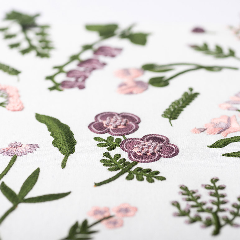 green and pastel purple botanical elements embroidered on white