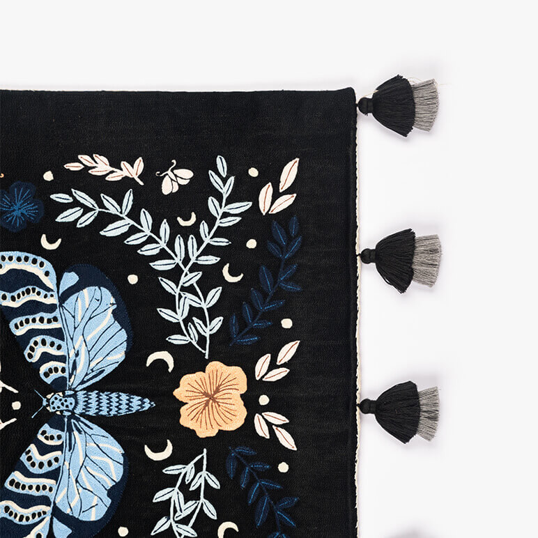 black and blue butterfly tapestry's corner shown with black and grey tassels placed around the bottom edge