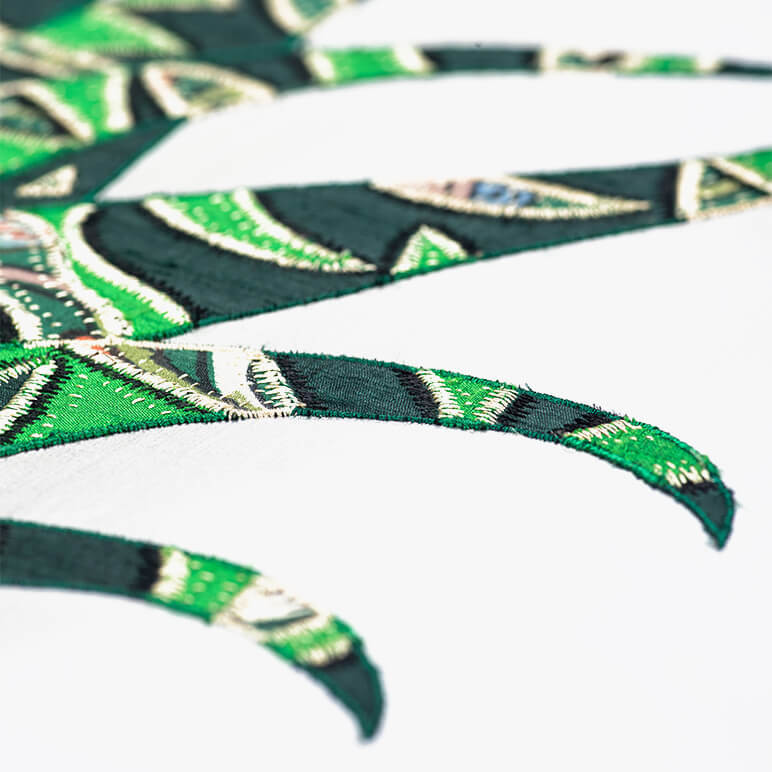 closeup view of the embroidery detail on a green patchwork textile wall art