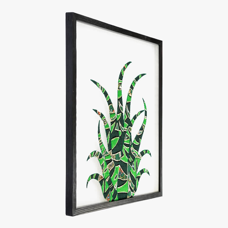 angled view of a framed cactus wall art in green with a black frame