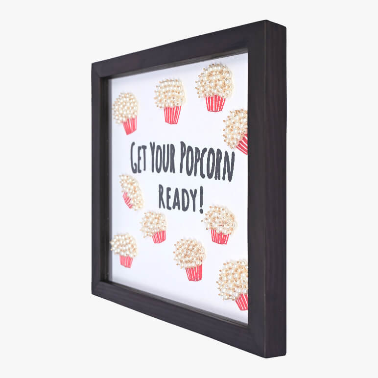 Right angle view of a typographical artwork that says get your popcorn ready, with embroidered popcorn motifs