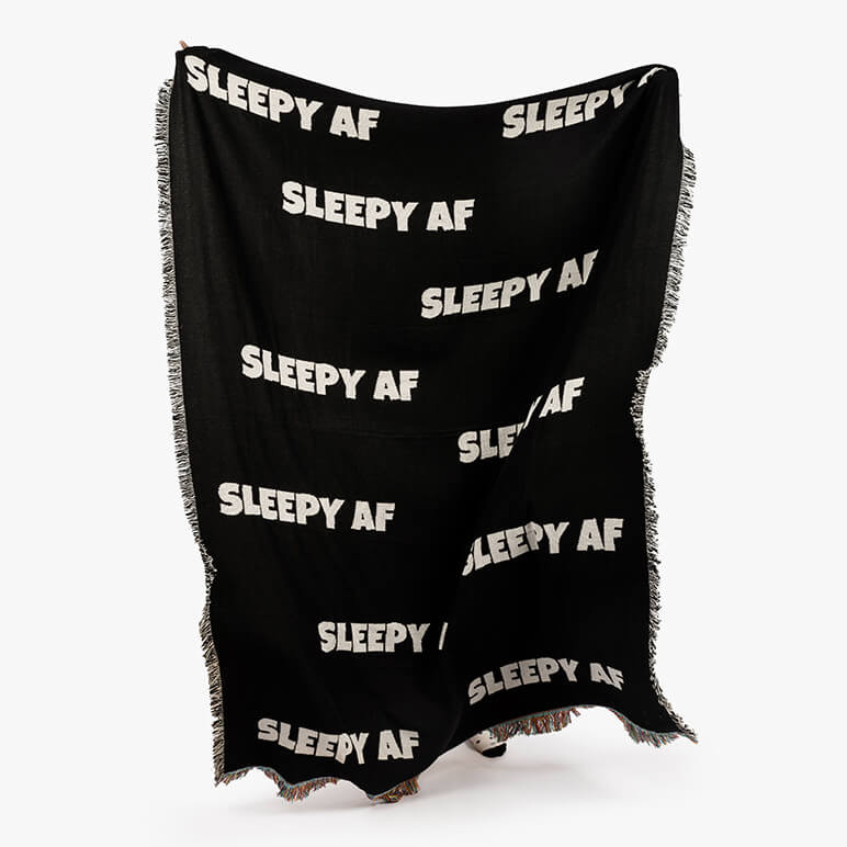black woven couch throw blanket with a typographic phrase in white