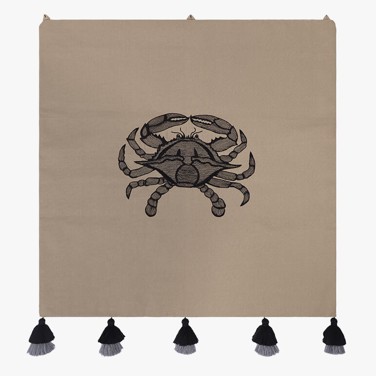 minimalistic crab art done in black thread work over an earthy toned cotton background, seen with five black tassels at the bottom