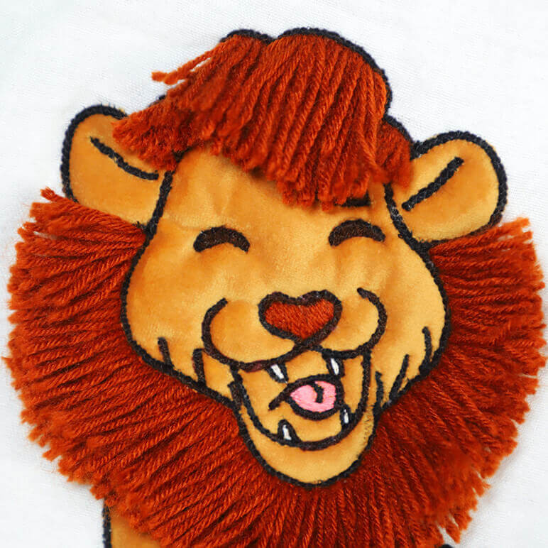closeup view of an embroidered lion in mustard and orange tones with woollen mane