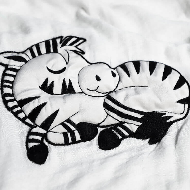 closeup view of an embroidered white and black cute looking zebra in a sleeping pose
