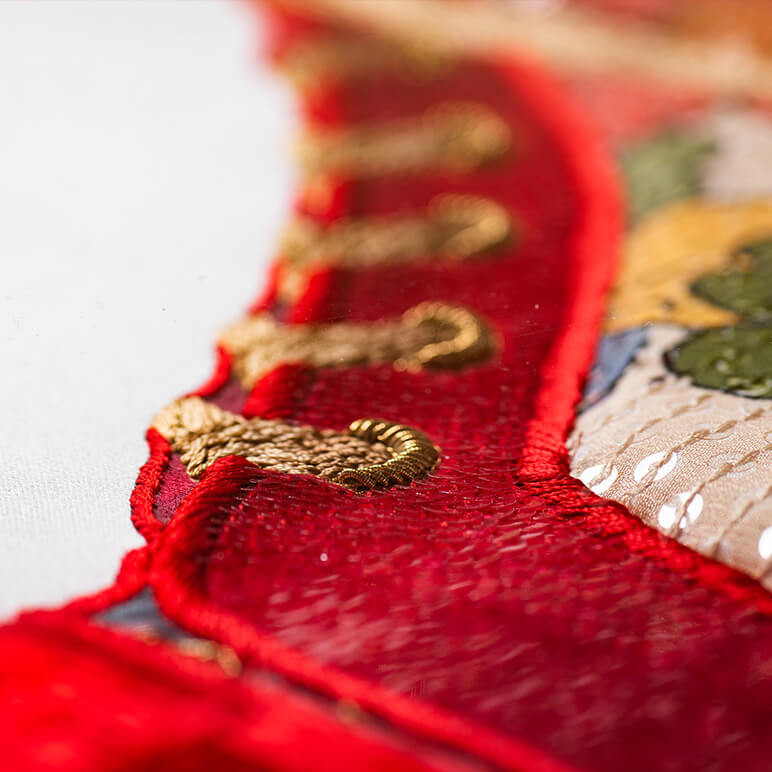 closeup view of the embroidery detail on a textile wall art featuring a red shoe