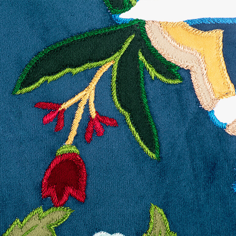 patchwork embroidery detail of a blue, red, yellow and green colored framed tapestry