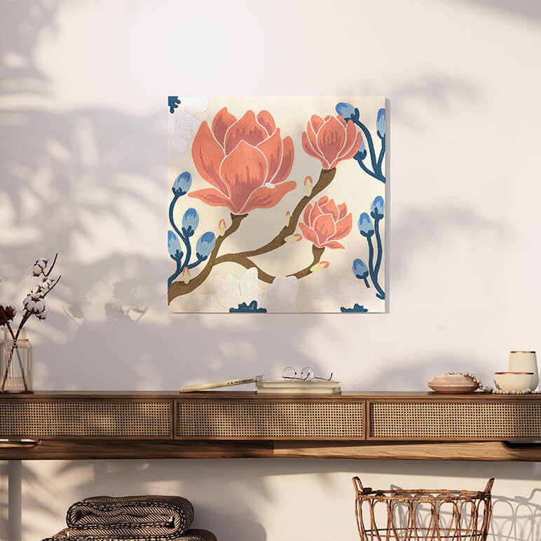 Styled shot of a textile artwork featuring embroidery with flowers, specifically Magnolia flowers, displayed on a beige wall
